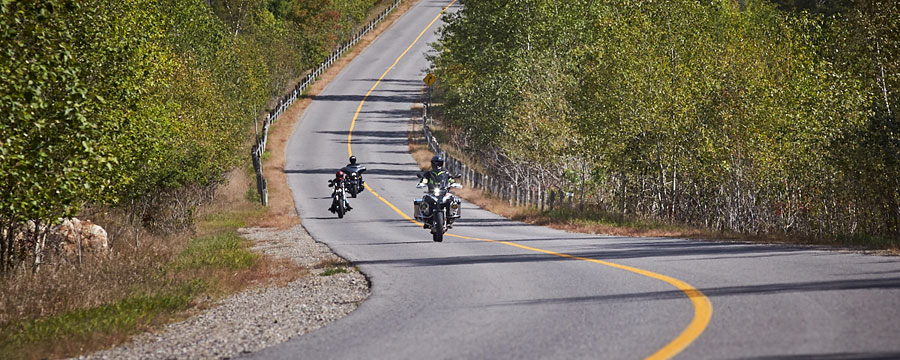 Motorcycle riding past a misty lake.